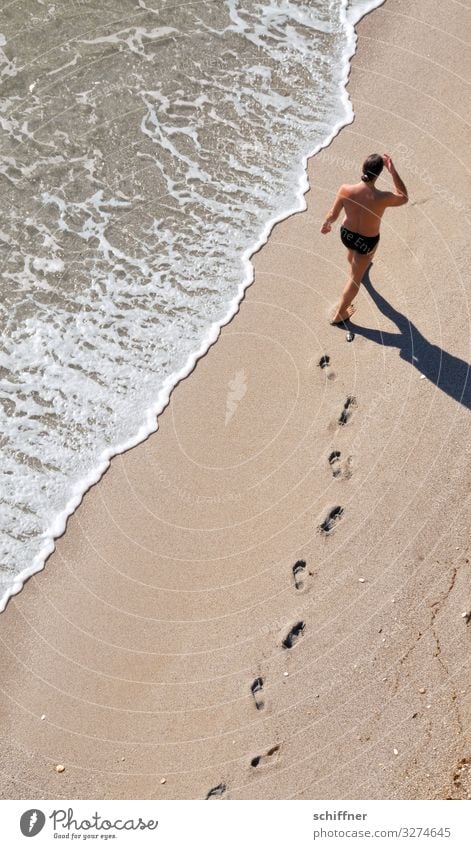 Mann läuft am Strand spazieren Urlaub Urlaubsstimmung urlaubsreif Strandspaziergang Meer Meeresufer Fußspur Barfuß Barfußstrand Meerwasser Wellen Gischt