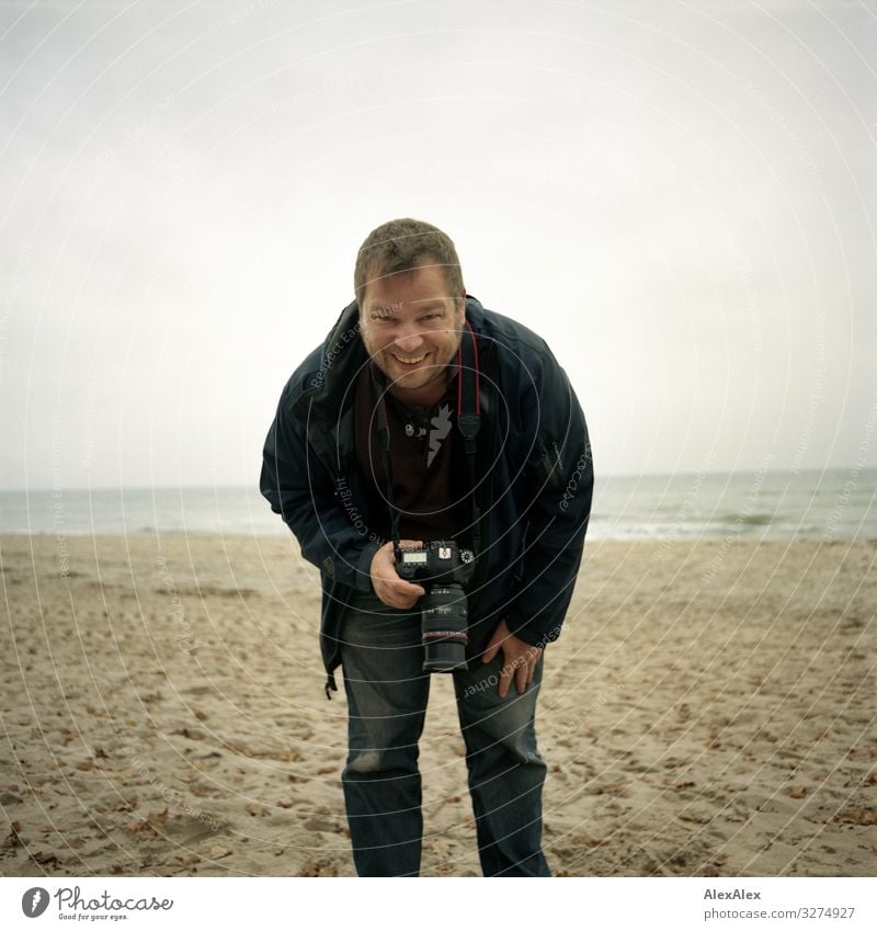 Fotograf am Ostseestrand Lifestyle Freude Ausflug Abenteuer Fotokamera Mann Erwachsene 30-45 Jahre Landschaft Herbst Strand Jeanshose Jacke blond kurzhaarig