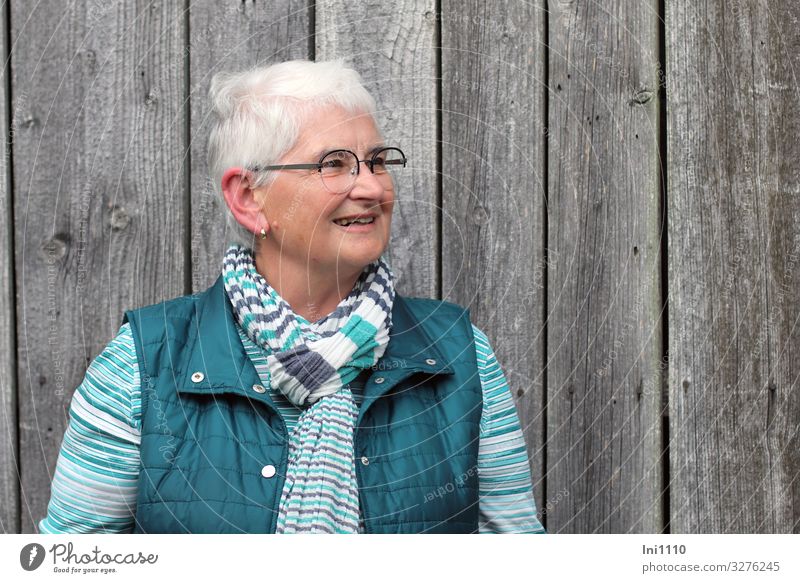 Seniorin schaut lächelnd nach links feminin Frau Erwachsene 1 Mensch 60 und älter Hütte Fassade Holz Freundlichkeit Fröhlichkeit grau grün türkis weiß