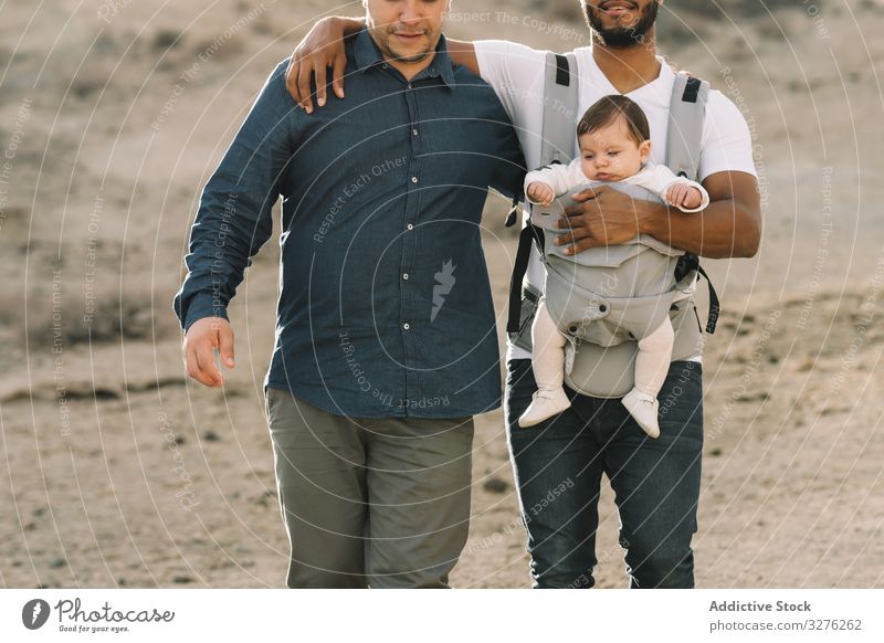 Unkenntlich verschiedene Männer, die mit Baby in der Natur spazieren gehen schwul Zusammensein Träger abstützen kuscheln Generation Interaktion lgbt