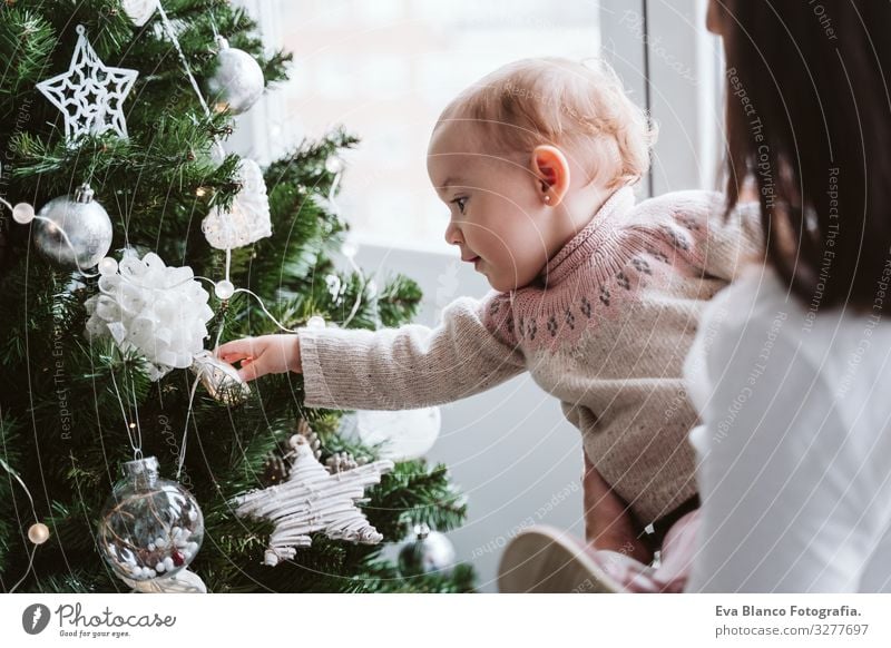 glückliche Mutter und Mädchen, die den Weihnachtsbaum schmücken Mutterschaft Glück niedlich Baby ein Jahr dekorierend Weihnachten & Advent Baum Freude