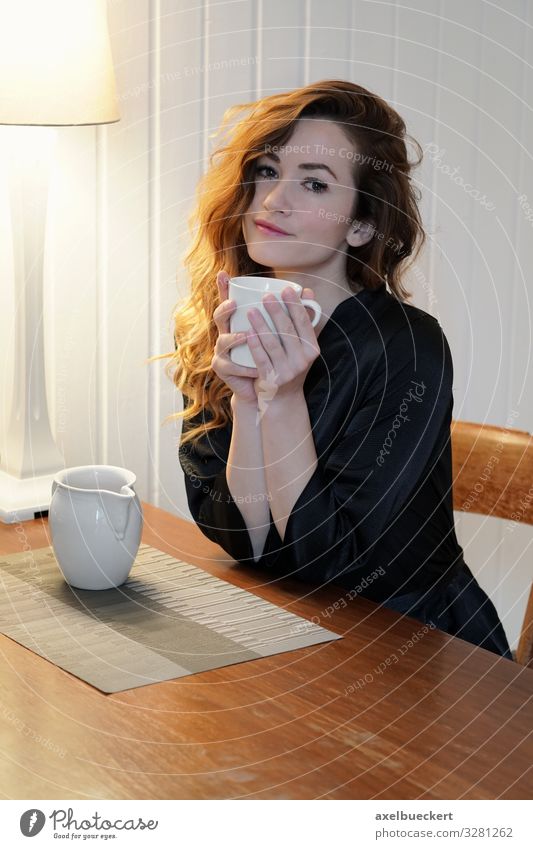 junge Frau mit Kaffee am Küchentisch Getränk trinken Heißgetränk Milch Tee Tasse Becher Lifestyle schön Wohlgefühl Zufriedenheit ruhig Freizeit & Hobby