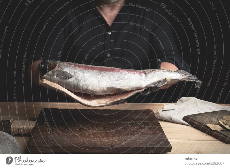 kopfloser Lachsfisch Fleisch Fisch Meeresfrüchte Ernährung Abendessen Tisch Küche Werkzeug Mann Erwachsene Hand Handschuhe Holz frisch groß braun schwarz