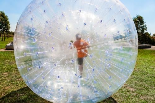 Kinder haben Spaß im Zorbing-Ball Freude Glück Freizeit & Hobby Abenteuer Sommer Sonne Sport Gras Wiese Hügel Kugel Tropfen Bewegung Fitness lachen