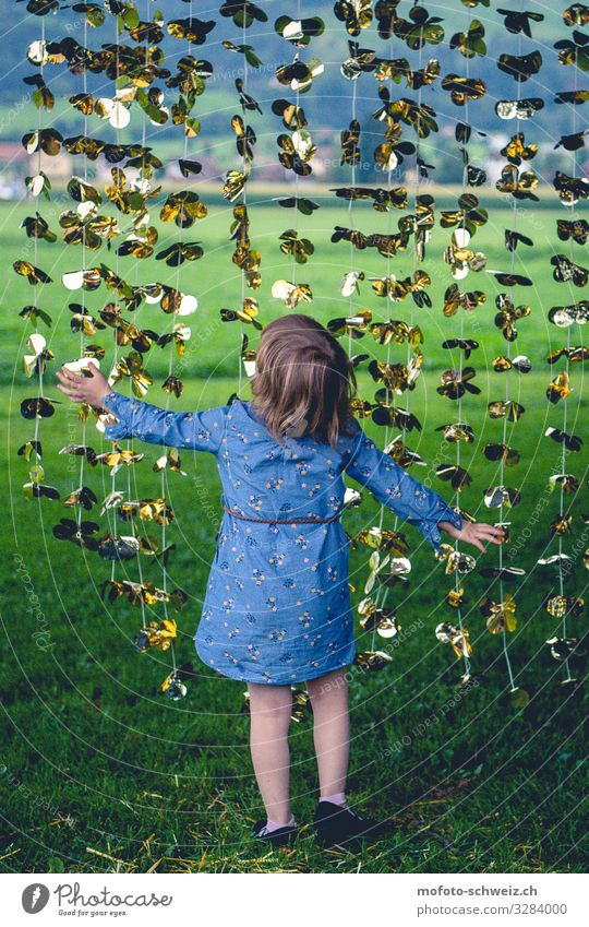 Kleines Mädchen auf Wiese unter gold-gelber Girlande 3-8 Jahre Kind Kindheit Sommer Kleid brünett Spielen Glück natürlich Neugier blau grün Freude Zufriedenheit