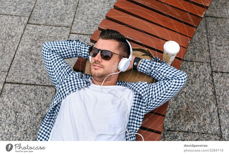 Mann mit Kopfhörern auf einer Bank liegend Lifestyle Erholung Freizeit & Hobby Entertainment Musik Arbeit & Erwerbstätigkeit Technik & Technologie Internet