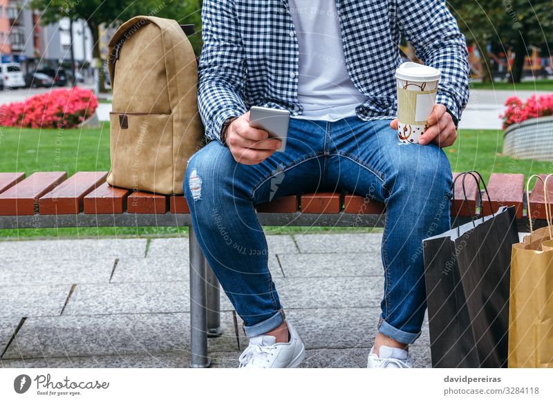 Mann, der mobil aussieht und auf einer Bank sitzt Lifestyle Körper Freizeit & Hobby lesen Garten Entertainment Arbeit & Erwerbstätigkeit Handy PDA