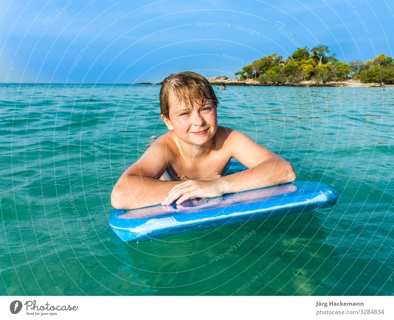 Junge schwimmt auf seinem Surfbrett Freude Glück Erholung Ferien & Urlaub & Reisen Strand Meer Insel Kind Jugendliche Natur Landschaft Himmel Horizont Wärme
