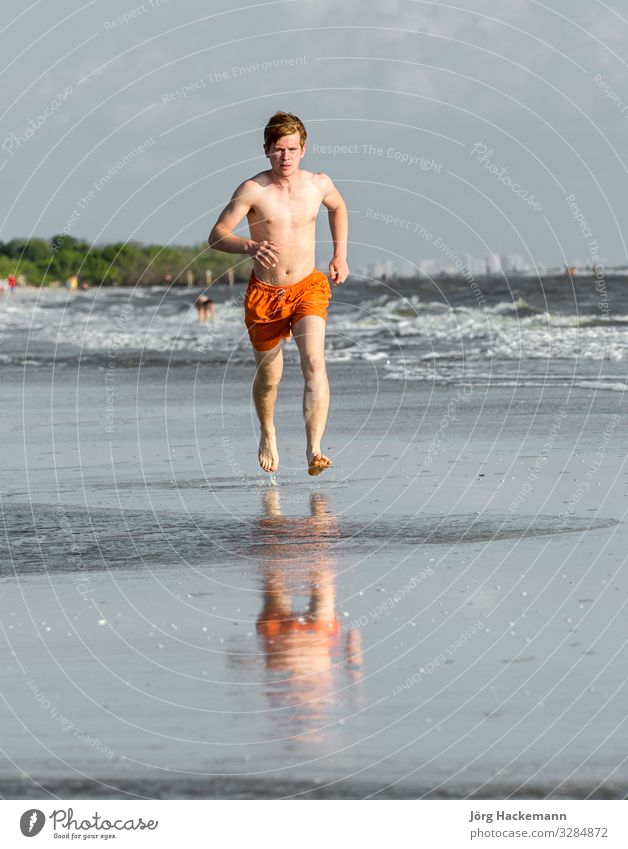 Teenager joggt gerne am Strand entlang Freude Glück Körper Ferien & Urlaub & Reisen Joggen Junge Jugendliche Sand Bewegung Fitness genießen Lächeln lachen