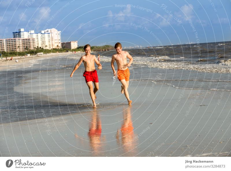 Teenager joggt gerne am Strand entlang Freude Glück Körper Erholung Ferien & Urlaub & Reisen Joggen Junge Jugendliche Sand Bewegung Fitness genießen Lächeln