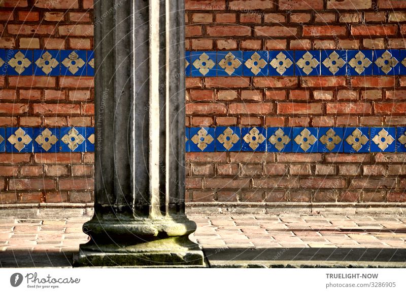 Teil einer Arkade im neobyzantinischen Stil mit kannelierter Säule vor gelblich-orangefarbenem Ziegelmauerwerk, das mit blau glasierten, gelb gemusterten Fliesen horizontal gebändert ist