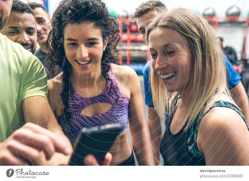 Athleten, die auf das Handy eines Sportlerkollegen schauen Lifestyle Freude Glück PDA Mensch Frau Erwachsene Mann Menschengruppe Fitness Lächeln Sporthalle