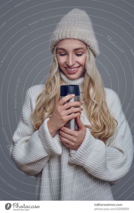Hübsche junge Frau in einem dicken Wollpullover und Strickmütze Getränk Gesicht Erwachsene 18-30 Jahre Jugendliche Pullover Hut blond Lächeln heiß hübsch