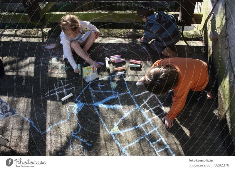 drei Kinder malen mit Kreide auf einen Betonboden Kinderspiel terasse Mädchen Junge Kindheit 3 Mensch 3-8 Jahre Zeichen Linie zeichnen Spielen klein Gefühle