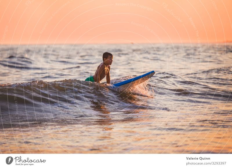Surfen bei Sonnenuntergang Junge 1 Mensch 8-13 Jahre Kind Kindheit Wasser Himmel Horizont Sommer Wellen Strand Badehose Freude Ferien & Urlaub & Reisen