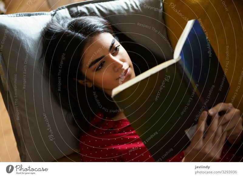 Persische Frau zu Hause beim Lesen auf der Couch Kaffee Lifestyle Haare & Frisuren Erholung Freizeit & Hobby lesen Winter Wohnung Sofa Wohnzimmer Mensch feminin