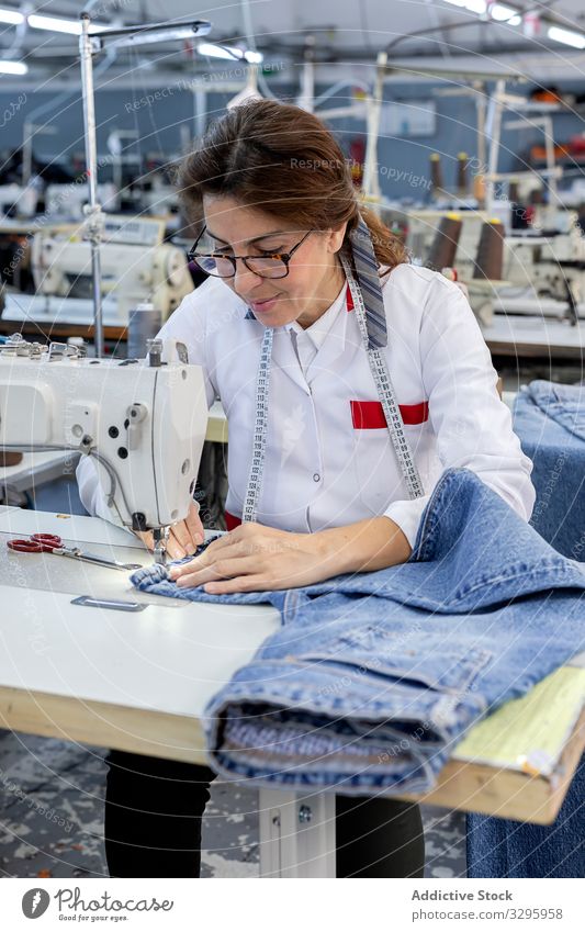 Frauenhände in einer Textilfabrik beim Nähen auf einer Industrienähmaschine. Fabrik Bekleidung Herstellung Arbeiter Maschine Hände Gewebe Hose Blue Jeans Beruf