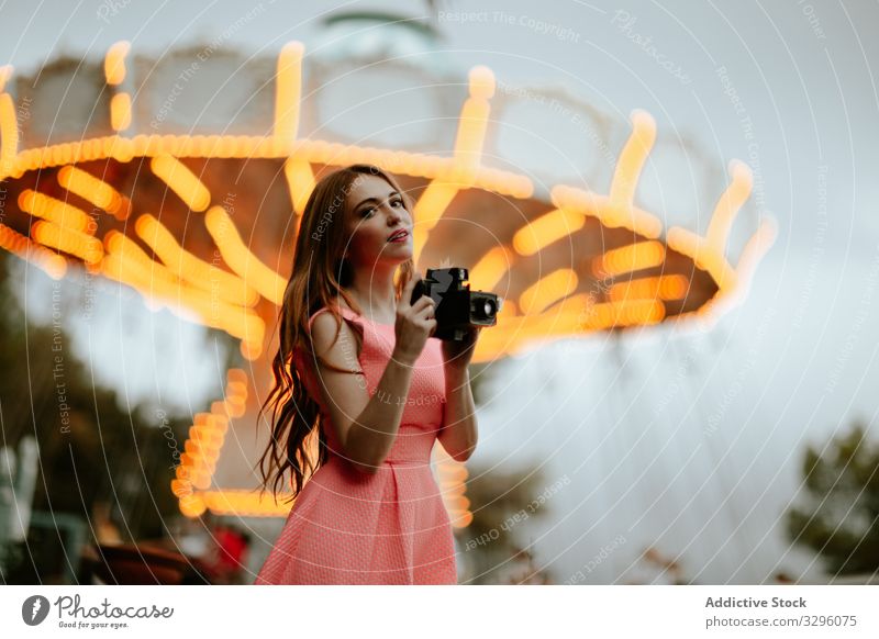 Tausendjährige Frau fotografiert mit Kamera im Vergnügungspark fotografierend Fotokamera Jahrmarkt trendy romantisch Kleid rosa Teenager Karussell tausendjährig