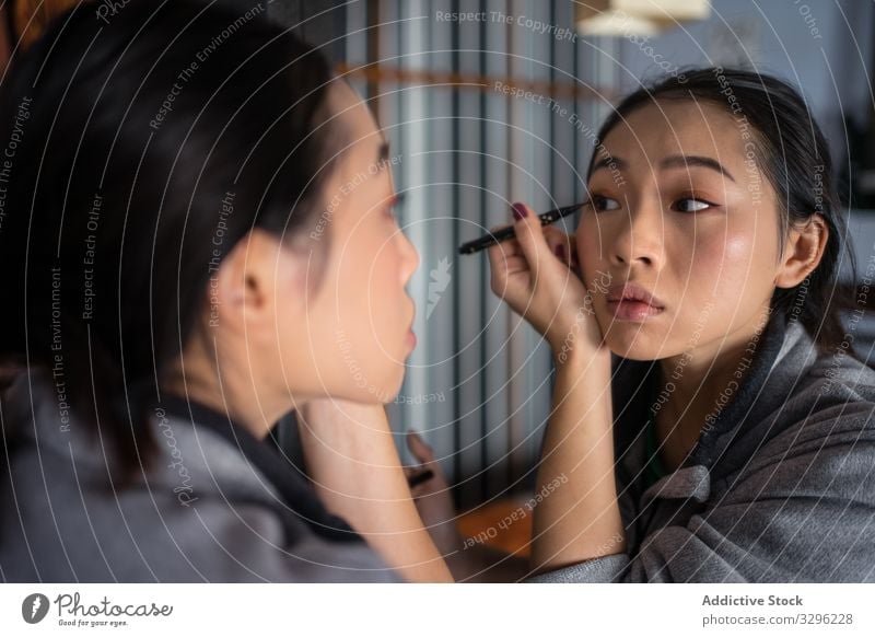Asiatin trägt Eyeliner vor dem Spiegel auf Frau Make-up Kajal Kosmetik lässig bewerben Schönheit Auge Reflexion & Spiegelung jung Gesicht Mode Pflege Teint
