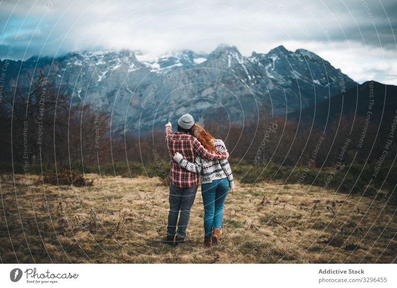 Charmante rothaarige Frau umarmt Mann in den Bergen mit geschlossenen Augen Paar umarmend Berge u. Gebirge Bonden amourös romantisch Partnerschaft Rasen reisen