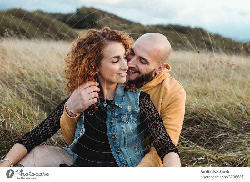 Verliebtes Hipster-Paar sitzt im Feld und genießt romantische Momente Umarmen Natur Glück jung Liebe Zusammensein Gras sitzen Umarmung kuscheln Romantik