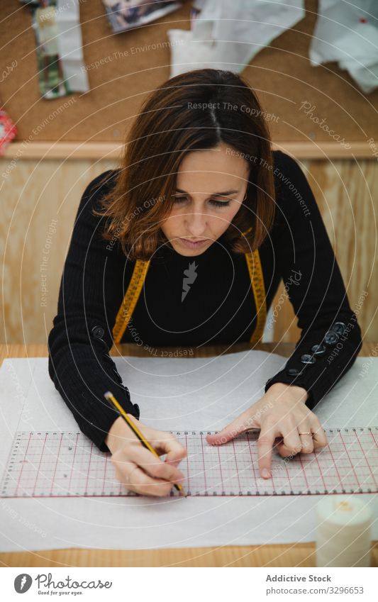 Schneiderinnen-Zeichnungsausschnitt in der Werkstatt zeichnen Ausschnitt Frau Tisch fokussiert Arbeit Erwachsener Designer Arbeitsplatz professionell