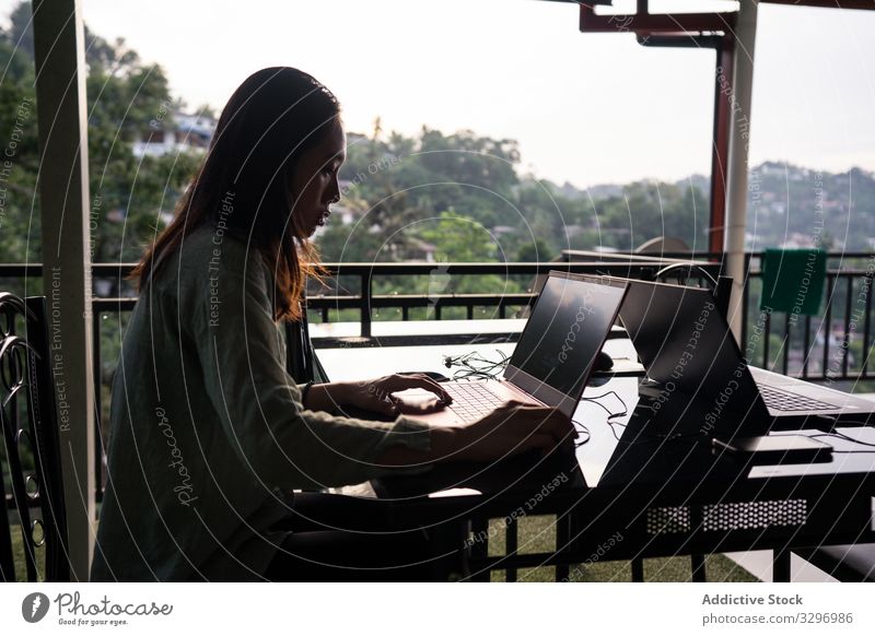Konzentrierte Freiberuflerin benutzt Laptop während einer tropischen Reise Frau freiberuflich benutzend Browsen reisen Tourismus Resort Terrasse Restaurant grün