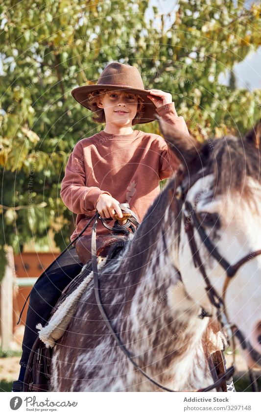 Junge mit Hut auf seinem braun gefleckten Pferd Kind Reiter Sommerzeit Freizeit Landschaft Kaukasier Urlaub Reiten Vollblut Schutzhelm 8-9 Jahre Lifestyle