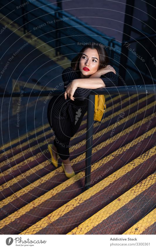 Frau in stilvollem Outfit lehnt auf Handlauf an Treppe modisch trendy Abenddämmerung Schatten stylisch Bekleidung Großstadt Straße Stehen jung Verschlussdeckel
