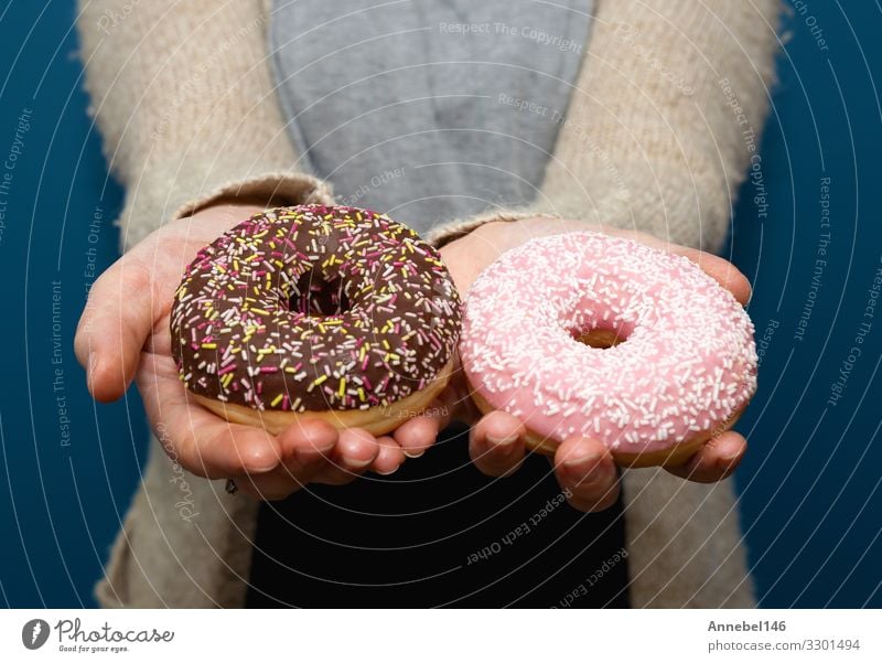 Frau hält einen köstlichen bunten Donut Dessert Frühstück Diät Haut Erwachsene Hand Finger lecker gelb rosa schwarz weiß Krapfen süß Snack vereinzelt