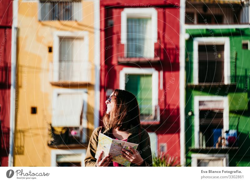 junge frau hält eine karte bei sonnenuntergang im freien. farbenfroher stadthintergrund. reisekonzept Frau Großstadt Landkarte mehrfarbig Hintergrundbild
