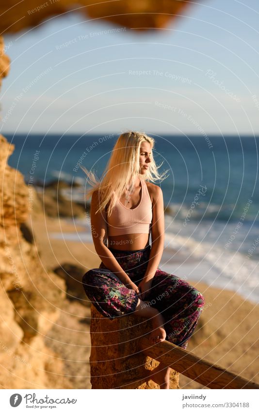 Junge Frau sitzt auf einer schönen Treppe und blickt mit goldenem Licht auf das Meer. Lifestyle Glück Körper Leben Erholung Meditation Freizeit & Hobby