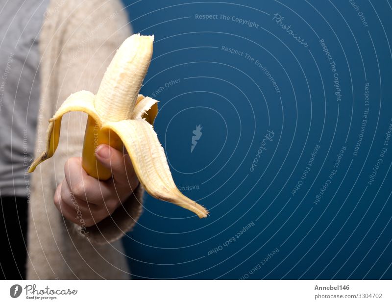 Person, die eine gelbe Bananenfrucht in der Hand hält Frucht Dessert Ernährung Vegetarische Ernährung Diät Design schön Mensch Frau Erwachsene Natur frisch hell