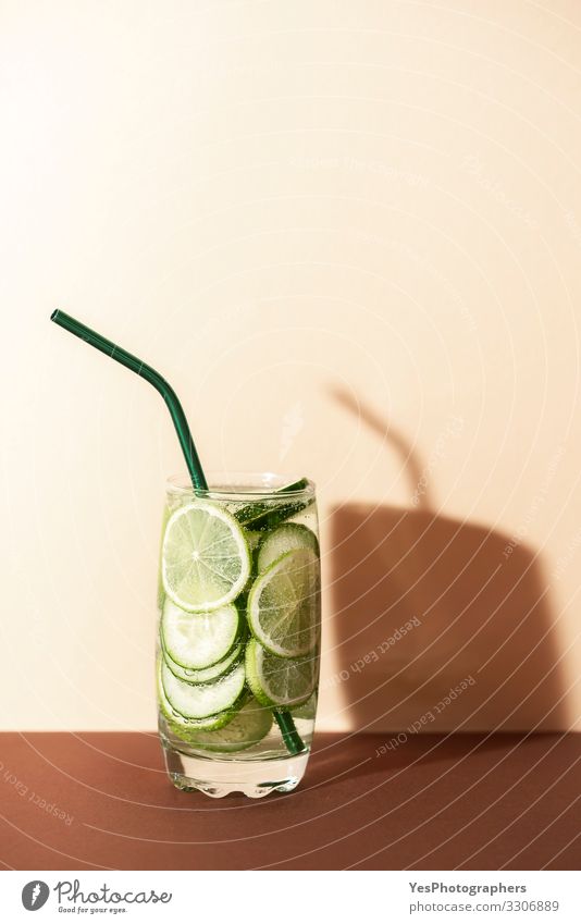 Gurken- und Limettenwasser. Kalte grüne Limonade. Frucht Getränk Erfrischungsgetränk Glas Trinkhalm rot antioxidatives Getränk Brauntöne Textfreiraum
