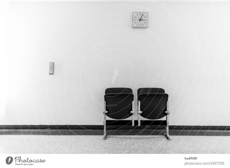Klappstuhlreihe mit Wanduhr auf einem Flur Gebäude Mauer Stuhl Sitzreihe Uhr warten Armut ästhetisch bedrohlich hässlich Krankheit modern retro Stadt grau ruhig