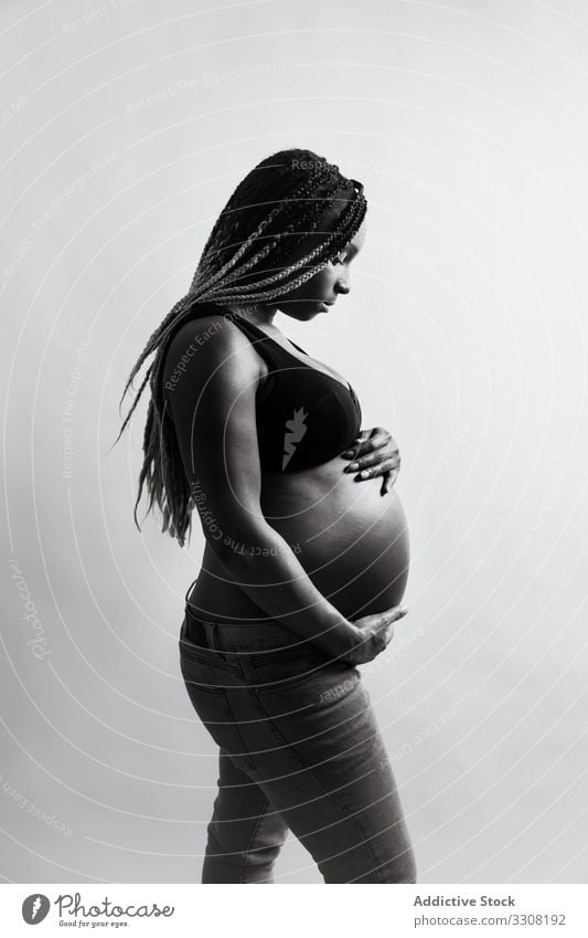 Glückliche schwangere afroamerikanische Frau hält Hände auf dem Bauch berührend heiter erwartend Mutterschaft Schwangerschaft Baby Kinderkriegen Vorfreude Liebe