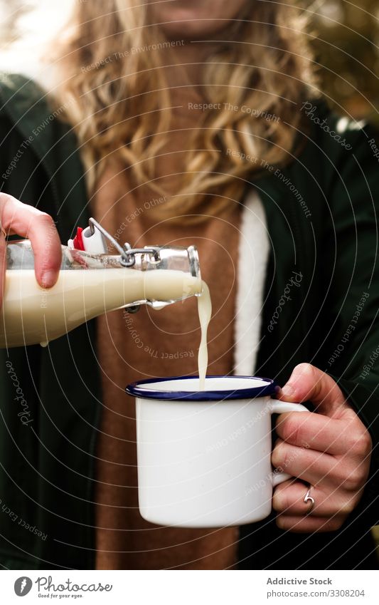 Anonyme Frau füllt während des Picknicks Becher mit Milch eingießen melken Molkerei Flasche lässig ländlich Landschaft Herbst trinken Tasse Getränk vorbereiten