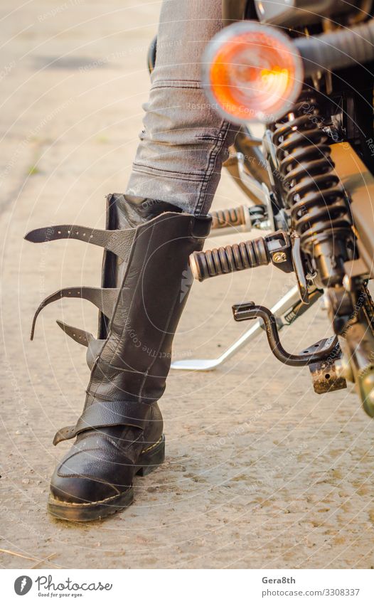 Fuß eines Biker-Mädchens in einem Motorradstiefel Stil Schuhe sitzen Schutz Motorradfahren Biker-Mädchenfuß Körperteil Jeans Stiefel Mädchenbein Grunge Bein