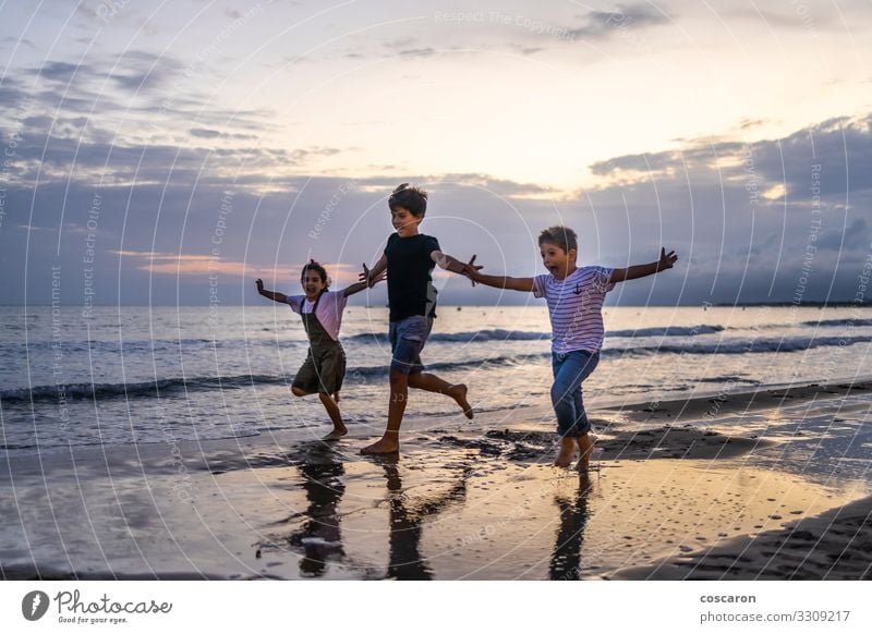 Drei Kinder laufen bei Sonnenuntergang am Strand Lifestyle Freude Glück Erholung Freizeit & Hobby Spielen Ferien & Urlaub & Reisen Abenteuer Freiheit Sommer