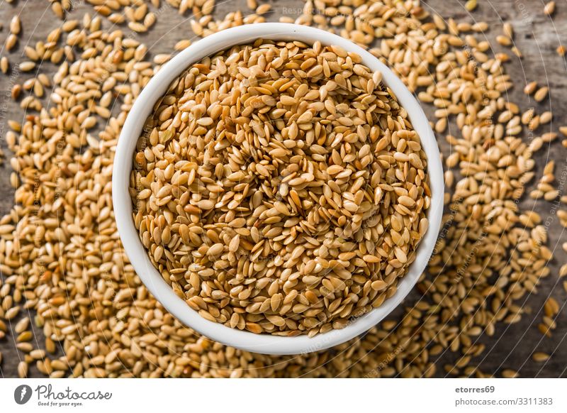 Goldene Leinsamen in weißer Schale auf Holztisch. gold Samen Saatgut Lebensmittel Gesunde Ernährung Speise Foodfotografie Gesundheit Diät Zutaten Getreide Korn