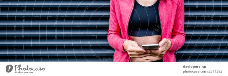 Sportlerin mit Mobiltelefon Lifestyle Handy PDA Internet Mensch Frau Erwachsene brünett Fitness stehen sportlich dünn schwarz Gitterrost-Hintergrund Mobile