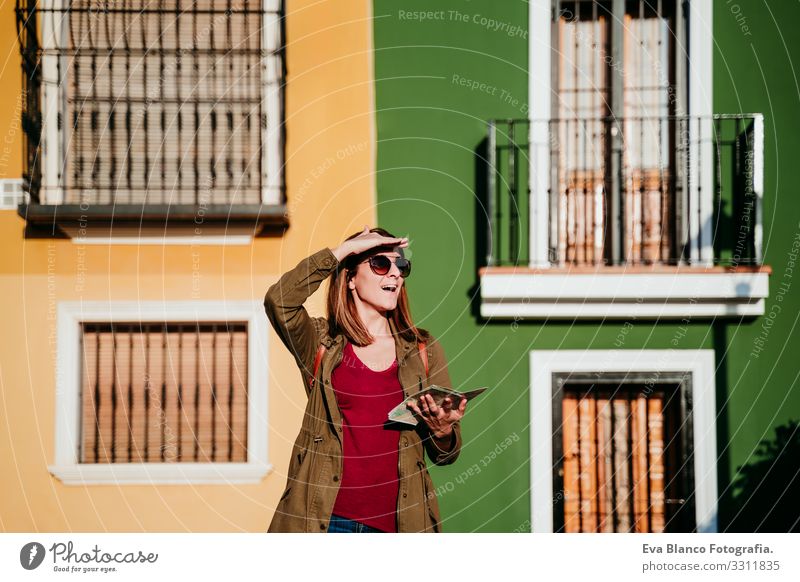 junge Frau beim Lesen einer Karte auf gelbem und grünem Hintergrund. reisekonzept Großstadt Landkarte mehrfarbig Hintergrundbild Ferien & Urlaub & Reisen