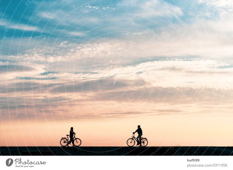 Silhouette von zwei Radfahrer die sich bei  Sonnenuntergang auf einem Deich auf Baltrum treffen Strand Fahrradfahren Mensch Paar Erwachsene 2 Natur Landschaft