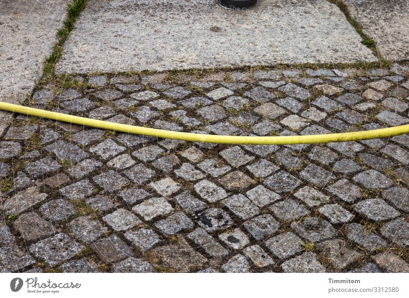 Ein Schlauch überquert den Platz gelb Pflastersteine Betonplatten Linien Stein Außenaufnahme Menschenleer Stadt Muster Rätsel