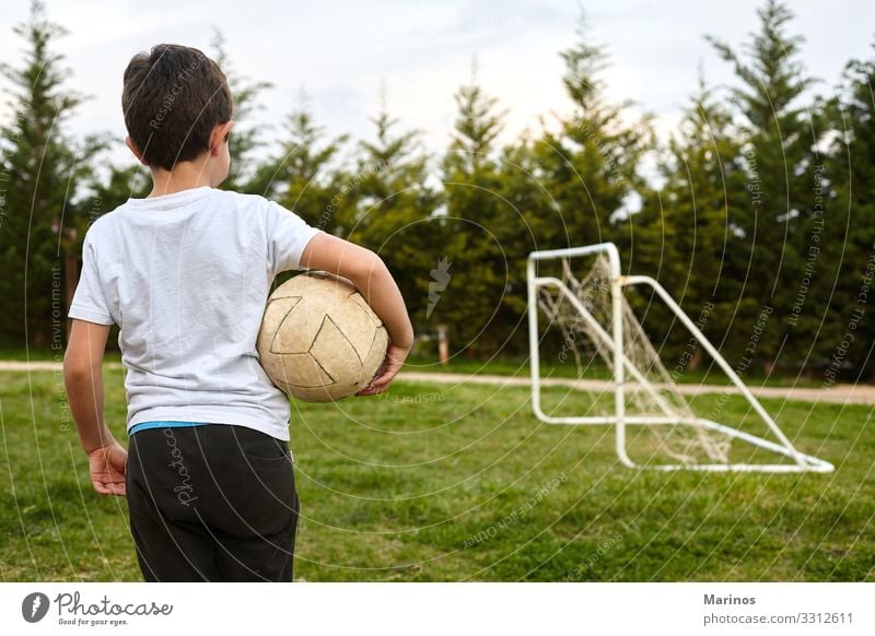 Kind, das einen Fußball auf dem Gartenfeld hält. Lifestyle Freude Glück Spielen Sport Mensch Junge Mann Erwachsene Gras Fröhlichkeit grün Ball Halt jung Kinder