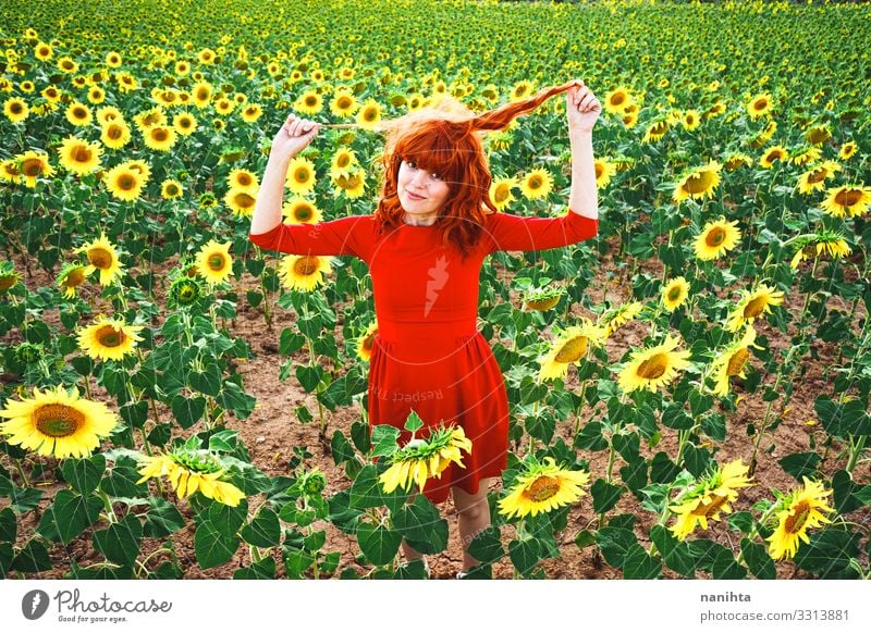 Reizende rothaarige Frau genießt den Tag auf einem Sonnenblumenfeld Rotschopf Fröhlichkeit Frühling jung genießen Freiheit Leben Blumen Sommer Feiertage Spaß