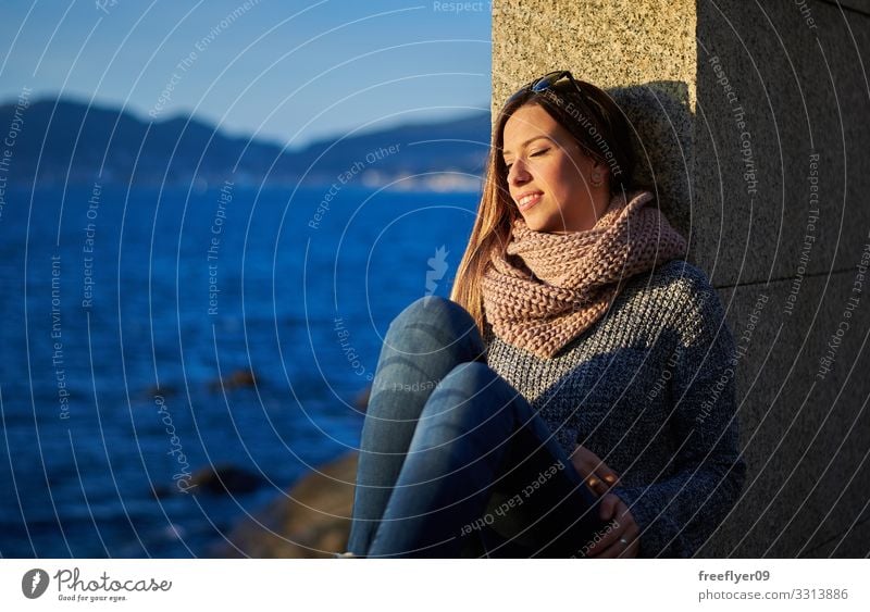 Junge Frau genießt das Sonnenlicht in der Nähe des Ozeans in Vigo jung genießend Meer MEER Wasser Steine Galicia Winter Herbst blau reisen Genuss wandern Küste