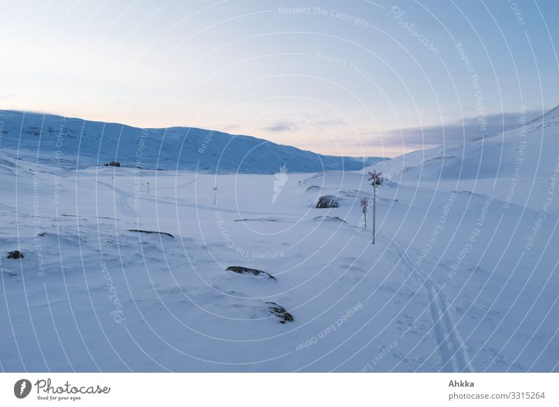 Eine Skispur in einer monochromen blaue Winterlandschaft, Wegmarkierungen für Schneescooter in der blauen Stunde blaue Stunde Schneelandschaft Arktis Dämmerung