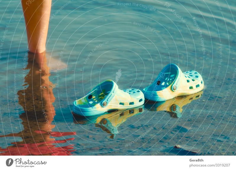 Gummipantoffeln schwimmen im klaren Wasser neben den weiblichen Beinen Meer Mensch Frau Erwachsene Paar Fuß Natur Teich See Schuhe Hausschuhe Bewegung natürlich