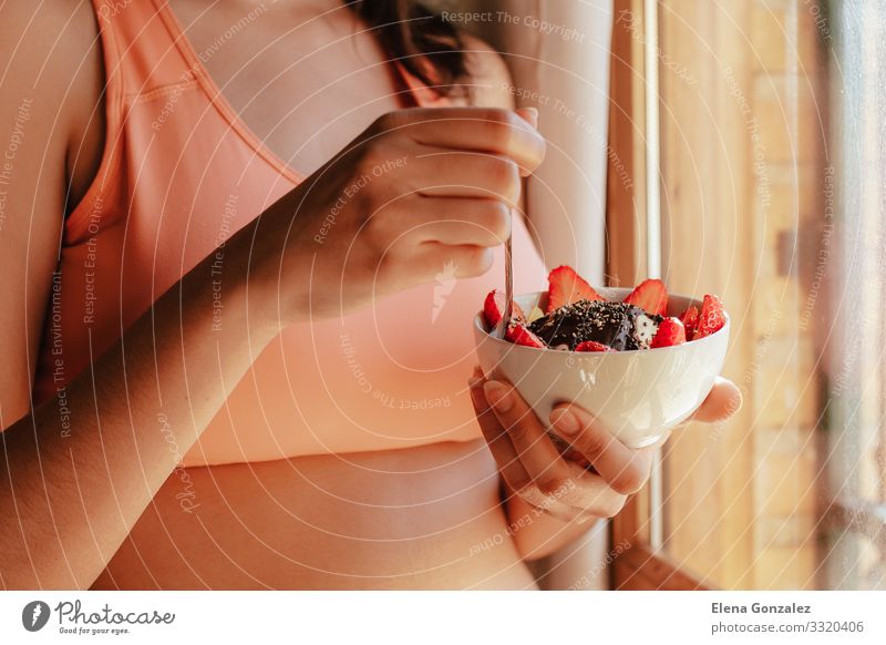 junge Frau mit Sport-BH beim Frühstücken Lebensmittel Joghurt Frucht Apfel Getreide Dessert Ernährung Essen Bioprodukte Vegetarische Ernährung Diät